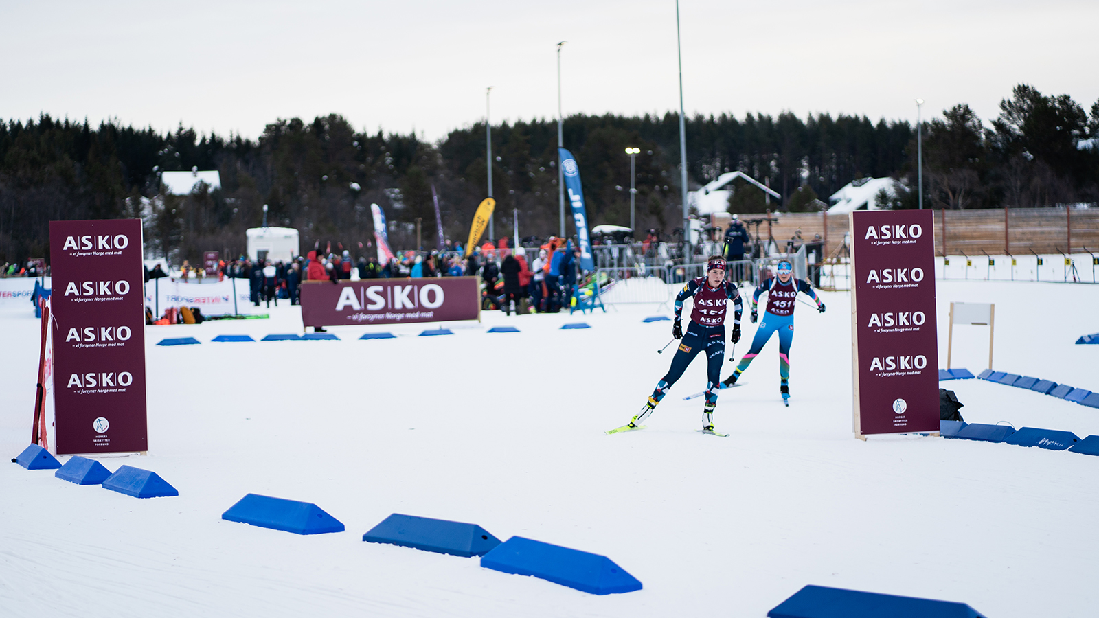 En skiskytter som går skirenn med ASKO profilerte bannere